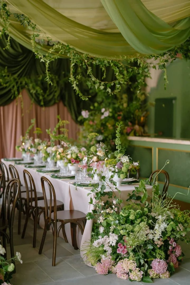 Long garden table under green drapes and flowers